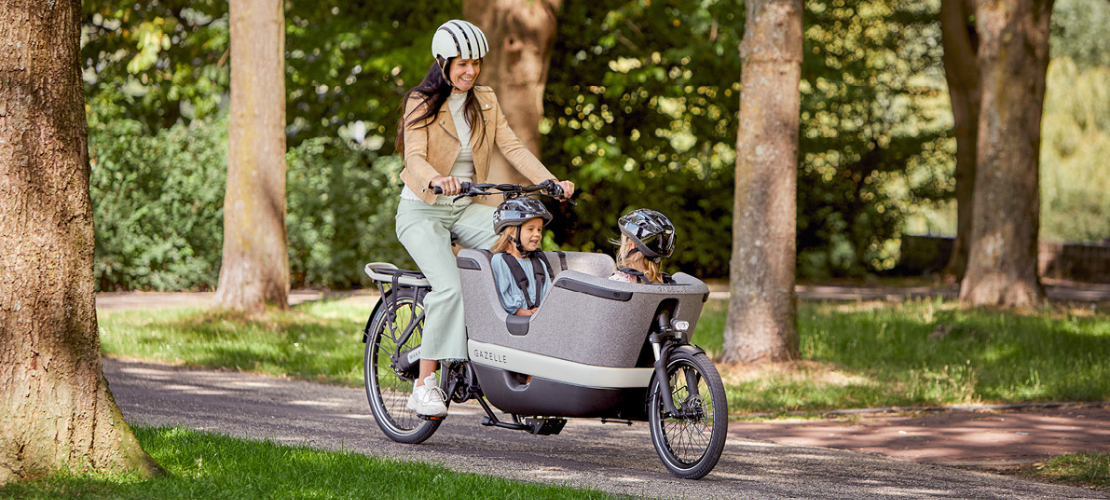 Moeder met kinderen met fietshelm in Gazelle bakfiets